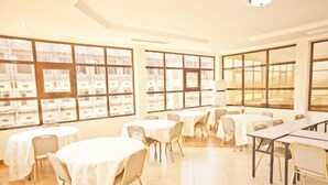 A hotel room with large windows, multiple tables, and chairs arranged for dining. - Nyumbani Hotels & Resorts - Moshi (Moshi)