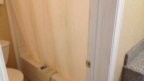Et badeværelse med toilet, badeforhæng og en dør til et andet rum.