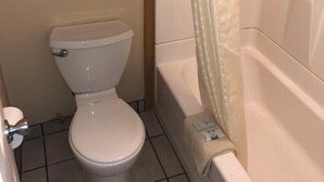 Et badeværelse med toilet, badekar og bruseforhæng.