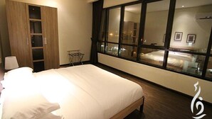 A hotel room with a large bed, a wardrobe with multiple doors, a window with a view of the city, and a small table with a lamp. - Rafa Homes  (Riyadh)