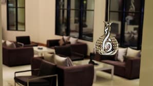 A modern lounge area with sofas and a coffee table, a decorative metal vase, and large windows. - Rafa Homes  (Riyadh)