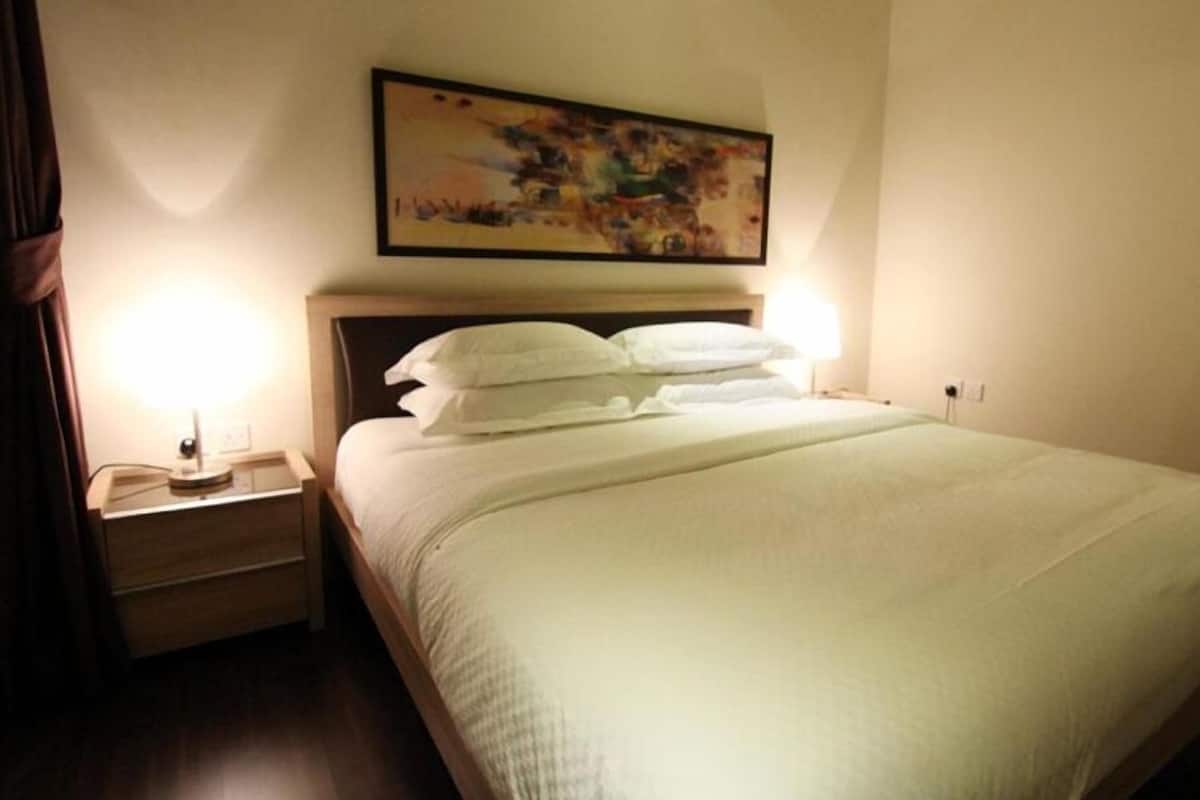 Un lit bien fait, avec du linge de lit blanc, dans une chambre d’hôtel.
