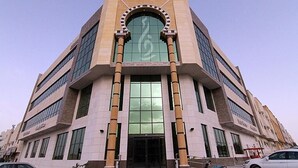 A modern building with a central entrance, large windows, and a distinctive architectural feature resembling a treble clef. - Rafa Homes  (Riyadh)