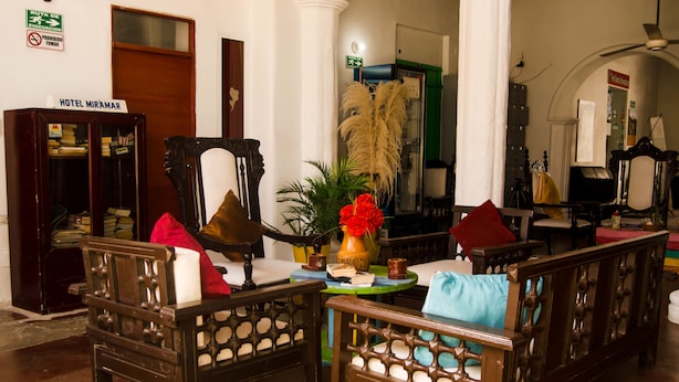 A hotel lobby with wooden furniture, a sign reading "Hotel Miramar," and a glass display case. - Hotel Miramar - Hostel (Santa Marta)