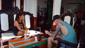 A room with a bed, a wooden chair, and a table with a bottle and sunglasses. - Hotel Miramar - Hostel (Santa Marta)