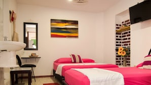 A hotel room with two beds, a sink, a chair, a painting, and a TV. - Hotel Miramar - Hostel (Santa Marta)