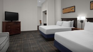Habitación de hotel con dos camas, un televisor en una cómoda y un cuadro en la pared.