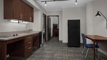 A modern kitchen with wooden cabinets, a countertop, a sink, and a dining area with a table and chair.