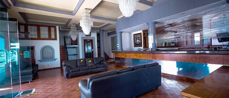 A spacious lobby with a large seating area, a reception desk, and a modern chandelier.