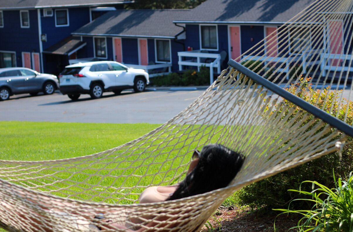 A hammock in a grassy area with a residential building in the background.