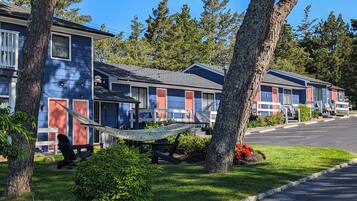 A row of blue and red motel buildings with a grassy lawn and trees.