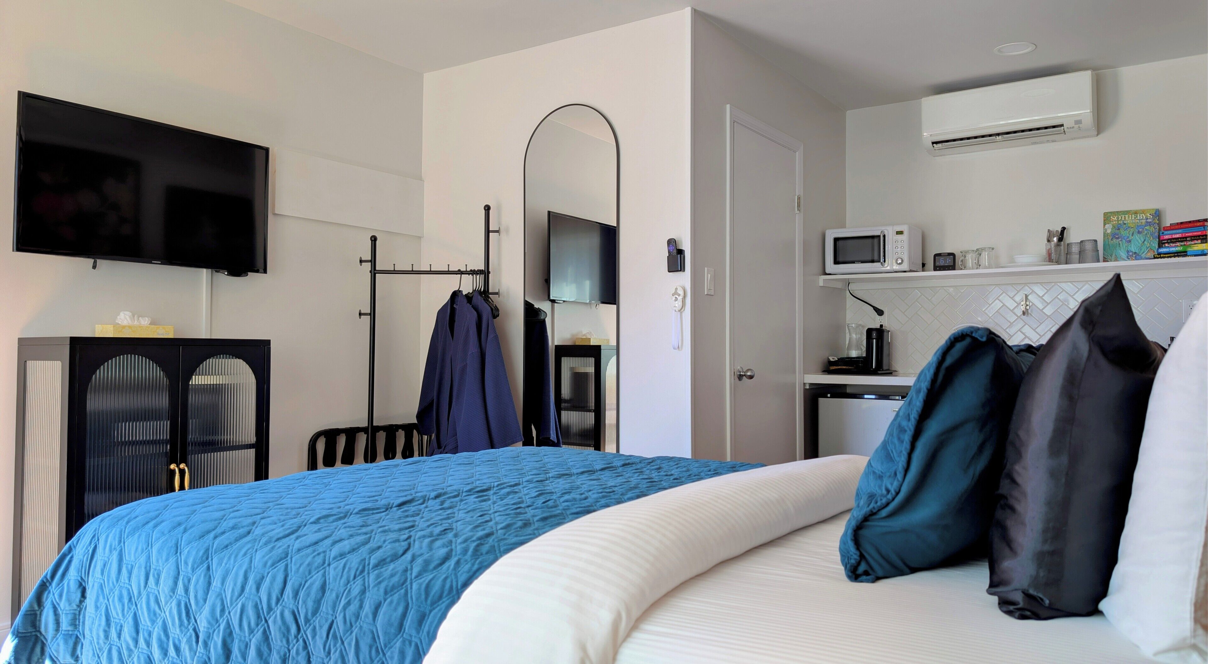 A hotel room with a bed, a TV, a microwave, a desk, and a wardrobe.