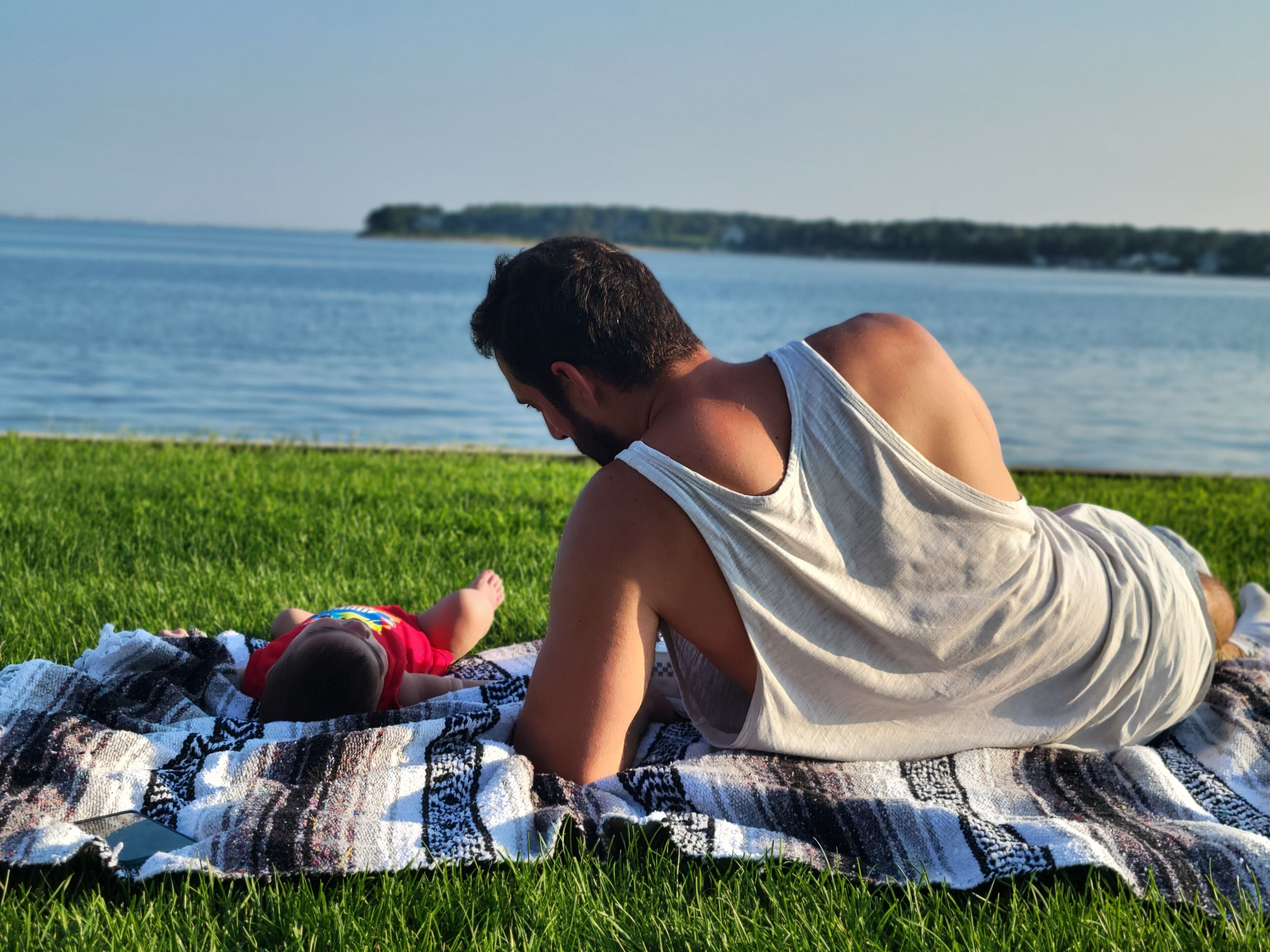 A person sitting on a blanket by a body of water.
