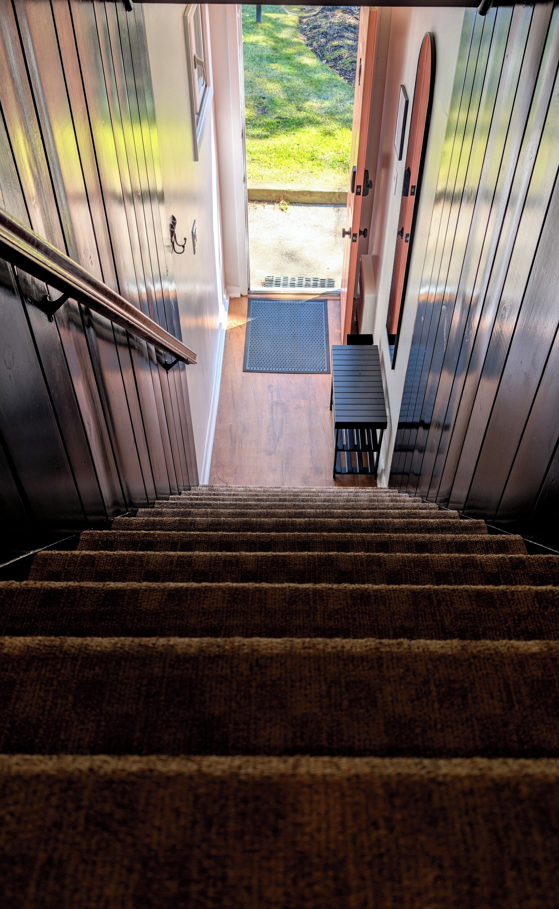 Eine Treppe führt zu einer Tür mit Blick auf einen grünen Garten.