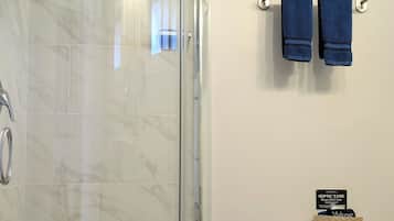 A bathroom with a glass shower enclosure, a toilet, and a sink.