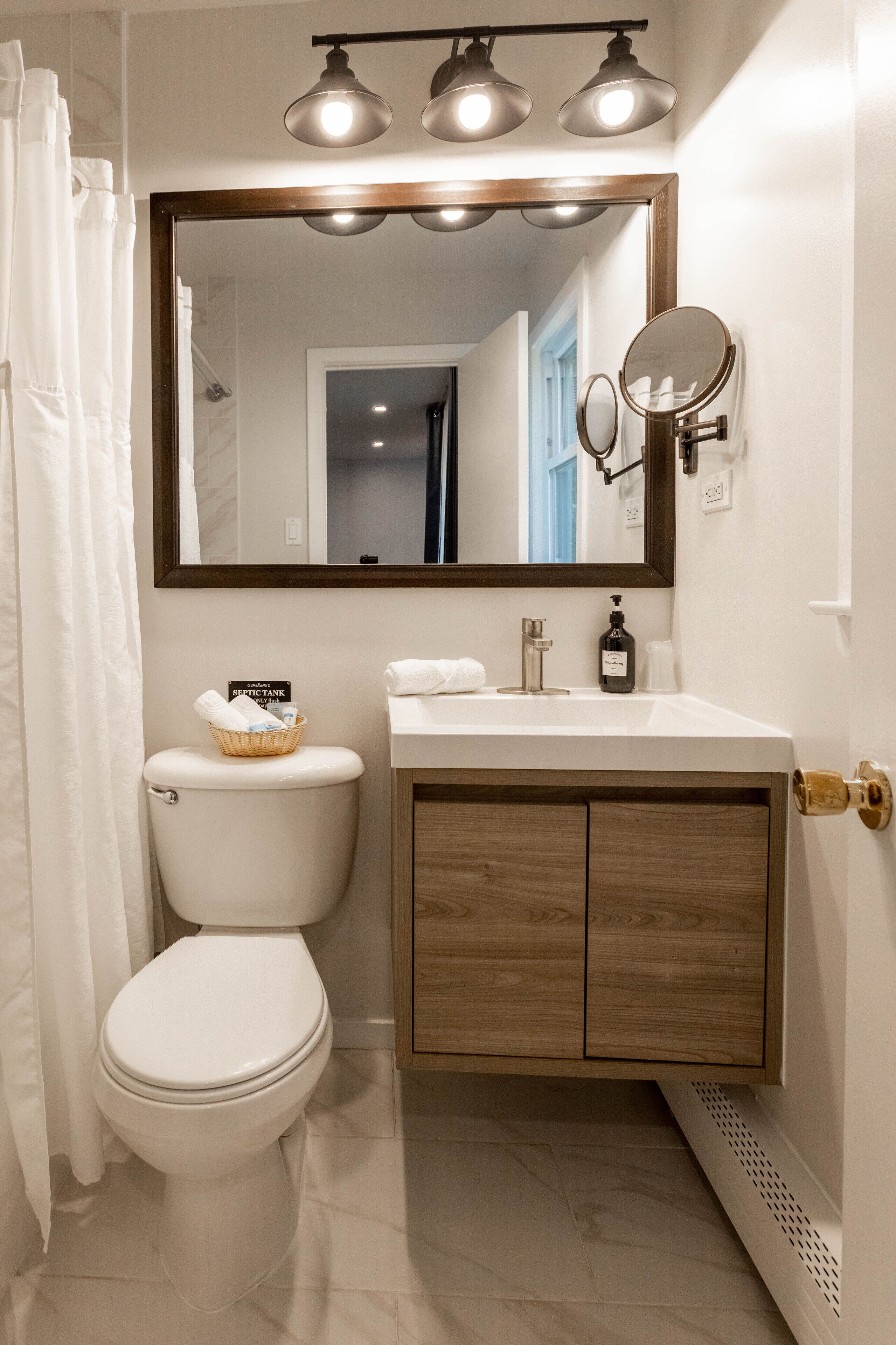 Un baño con inodoro, lavabo, espejo y cortina de ducha.
