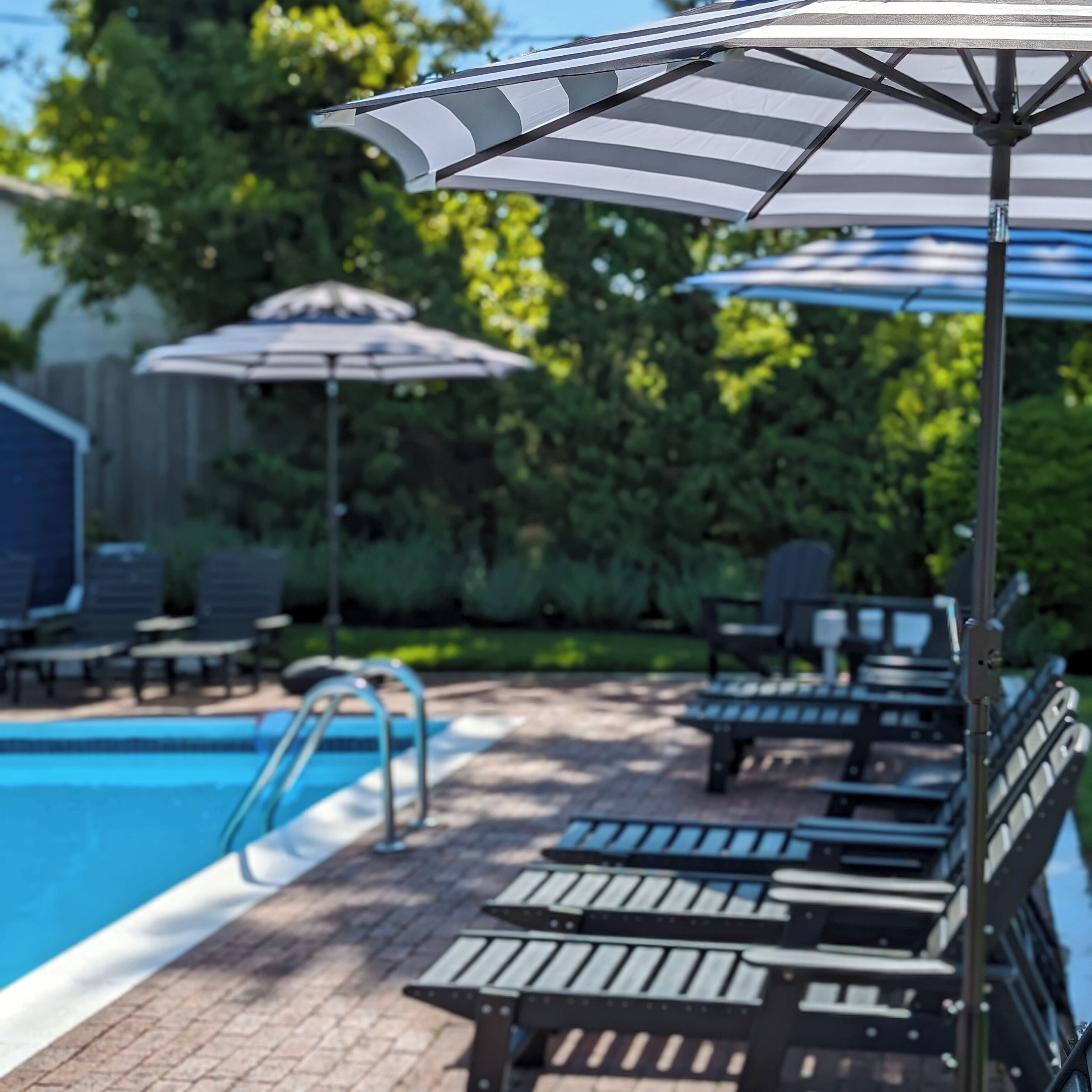 Un área junto a la piscina con sillones de descanso y sombrillas.