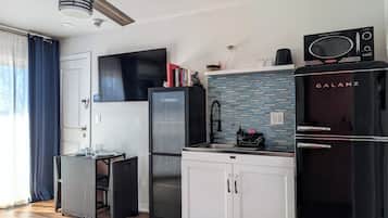 Una cocina compacta equipada con refrigerador, microondas y pileta.
