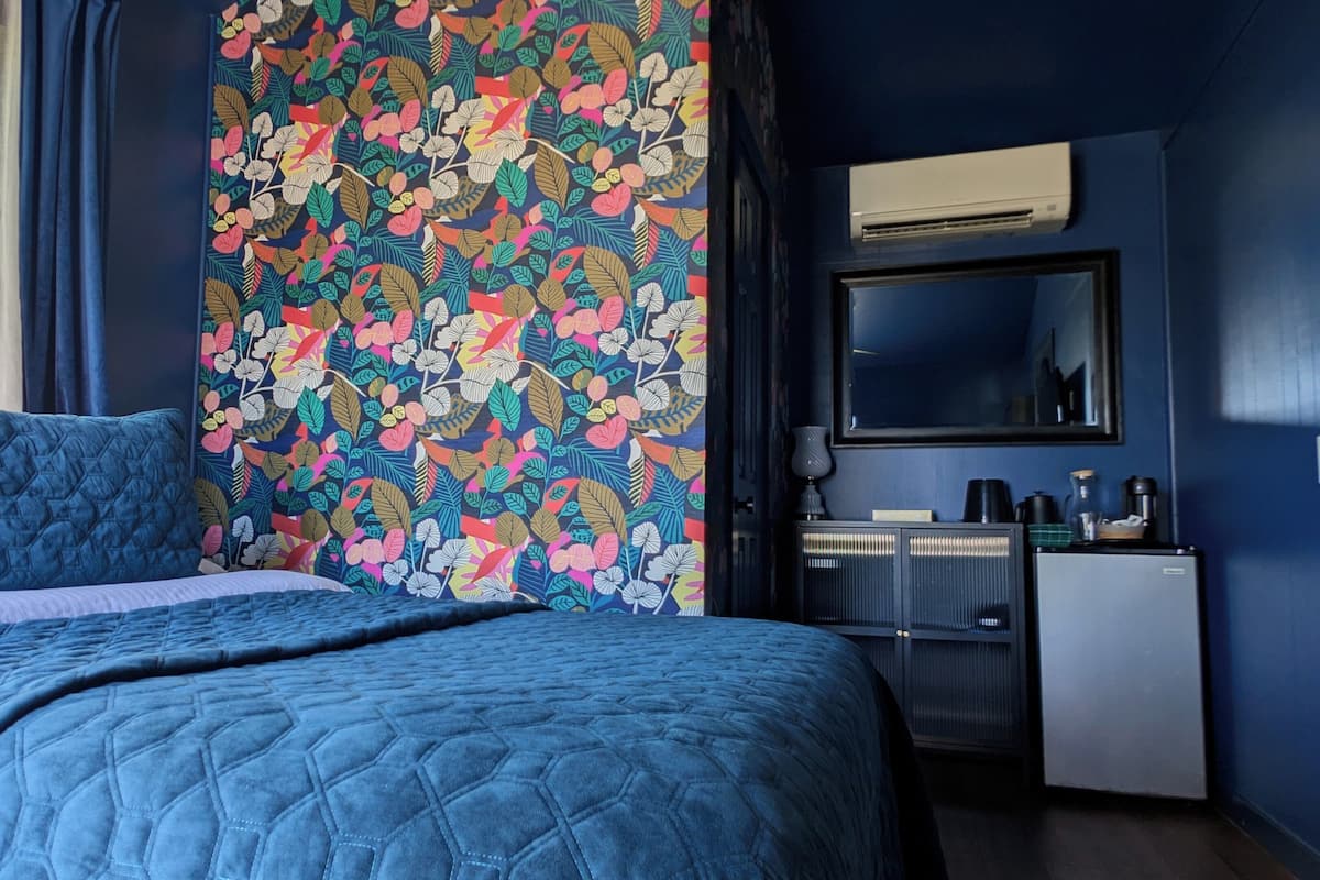 Un dormitorio con cama, cómoda, espejo y aire acondicionado.