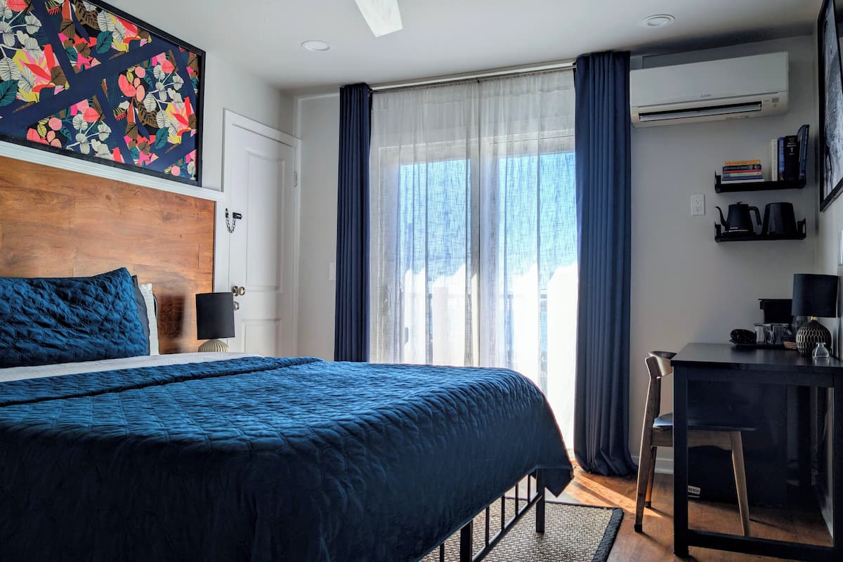 Un dormitorio con cama, escritorio, silla y ventana con cortinas.