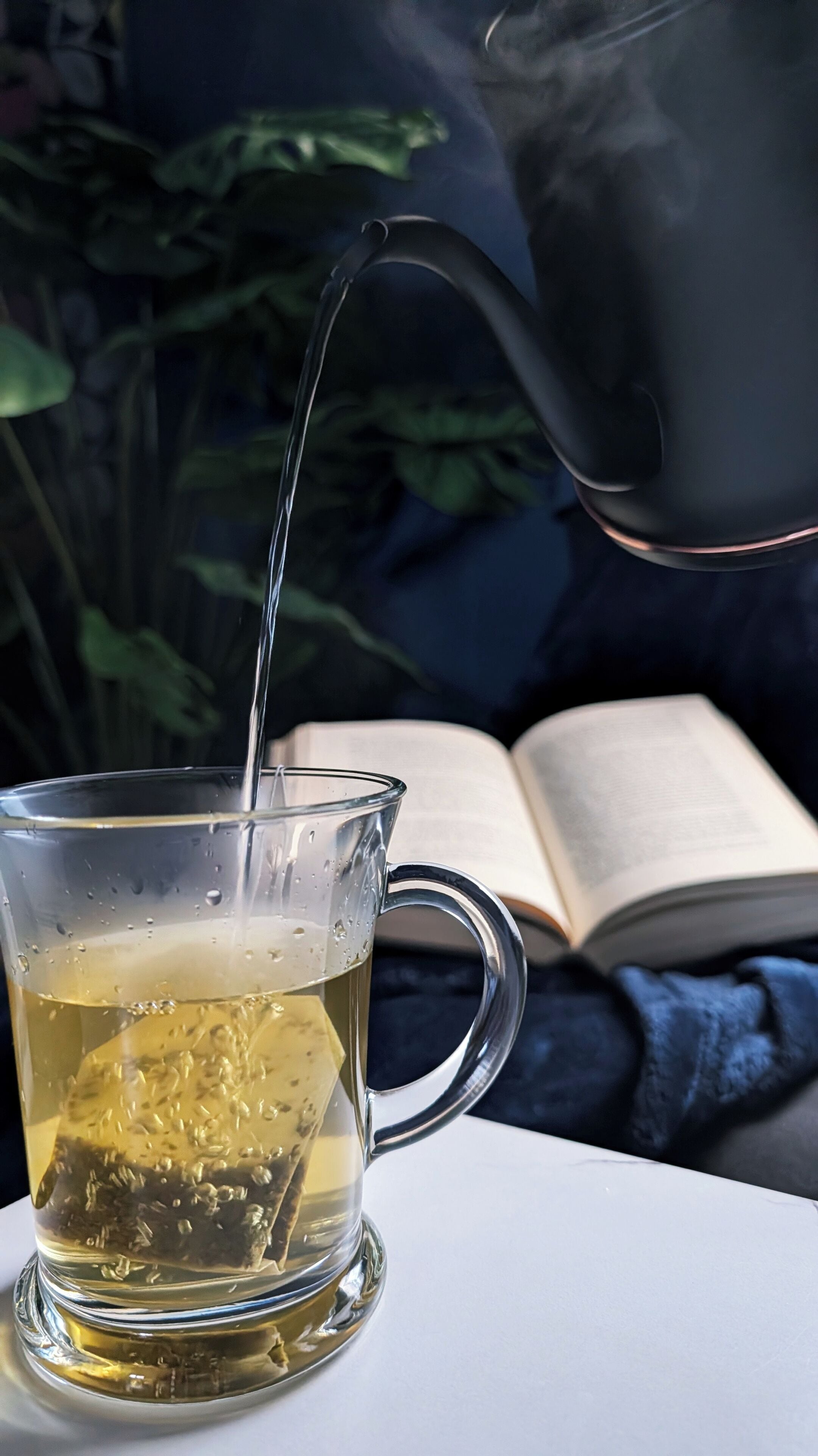 Una taza de vidrio transparente sobre una mesa, con té siendo servido.