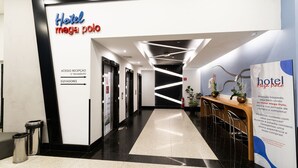 A hotel reception area with a modern design, including a reception desk, a waiting area with chairs, and directional signage for the reception and elevators. - Hotel Mega Polo (São Paulo)