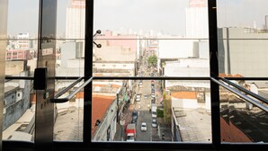 A view from a high-rise building with large windows, overlooking a cityscape with buildings and streets. - Hotel Mega Polo (São Paulo)