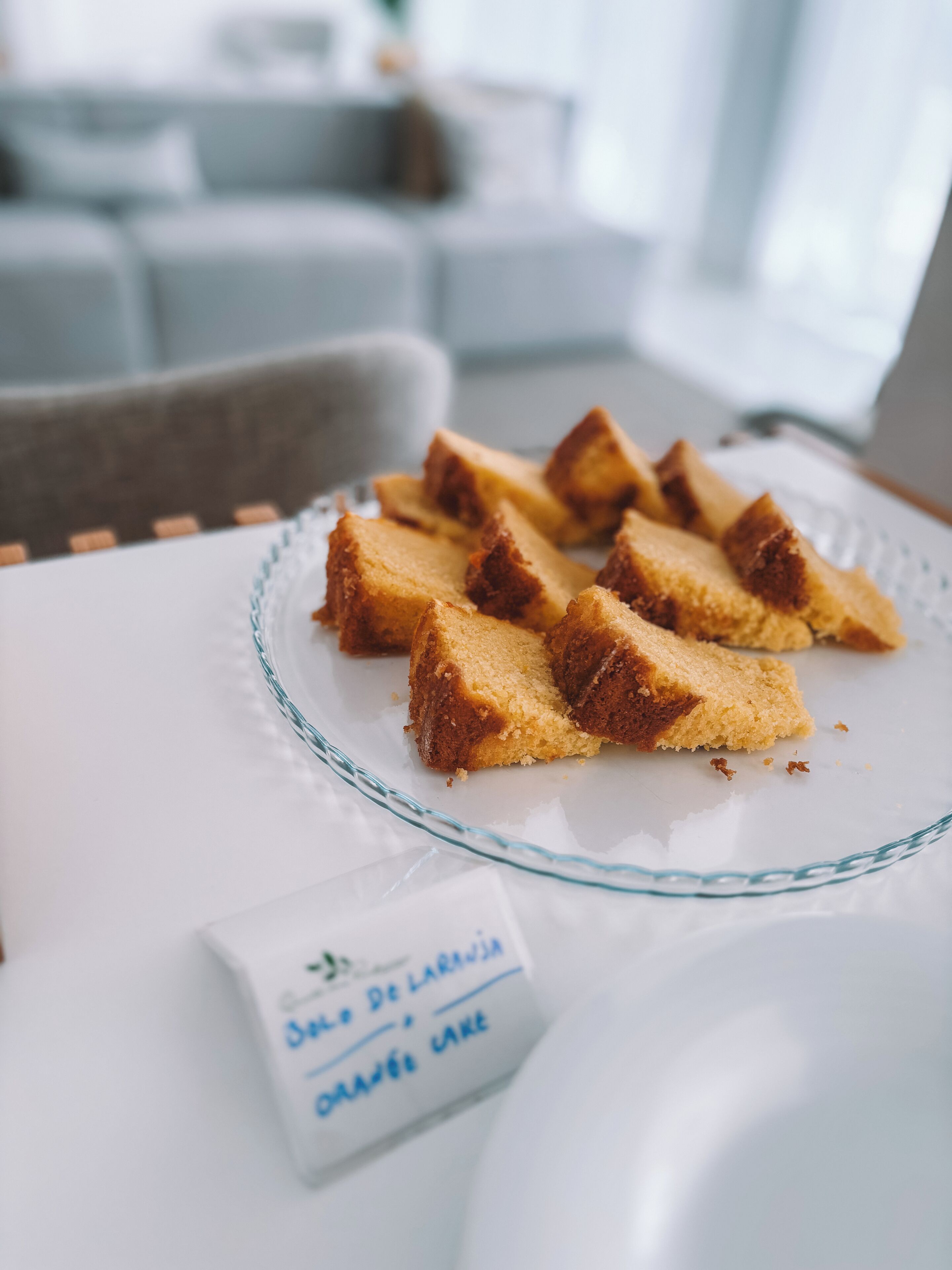 A glass plate with slices of cake on a white tablecloth.