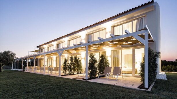 Una casa moderna con un porche cubierto, ventanas amplias y un césped cuidado.