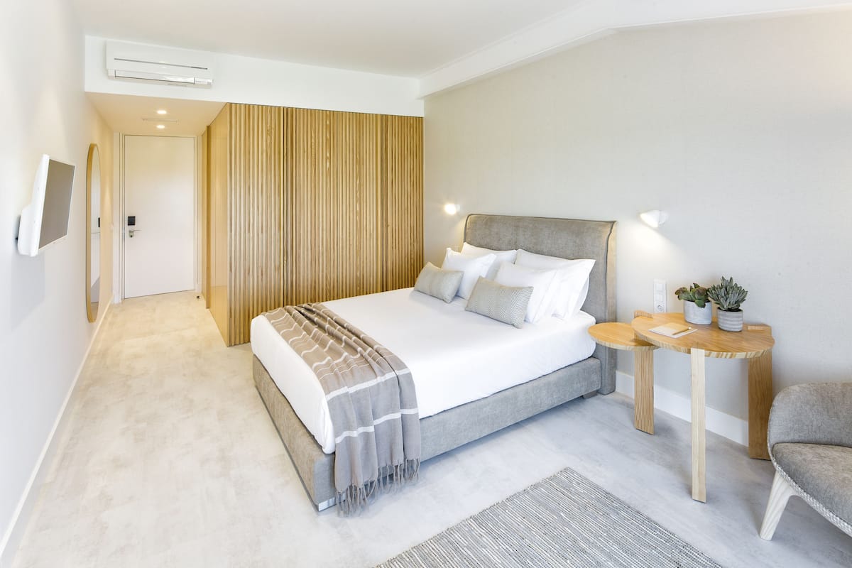 Une chambre moderne avec un grand lit, des tables de chevet et un petit coin salon.