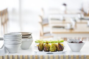 Uma mesa com tigelas de figos e cerejas, um prato de aspargos e tigelas empilhadas.