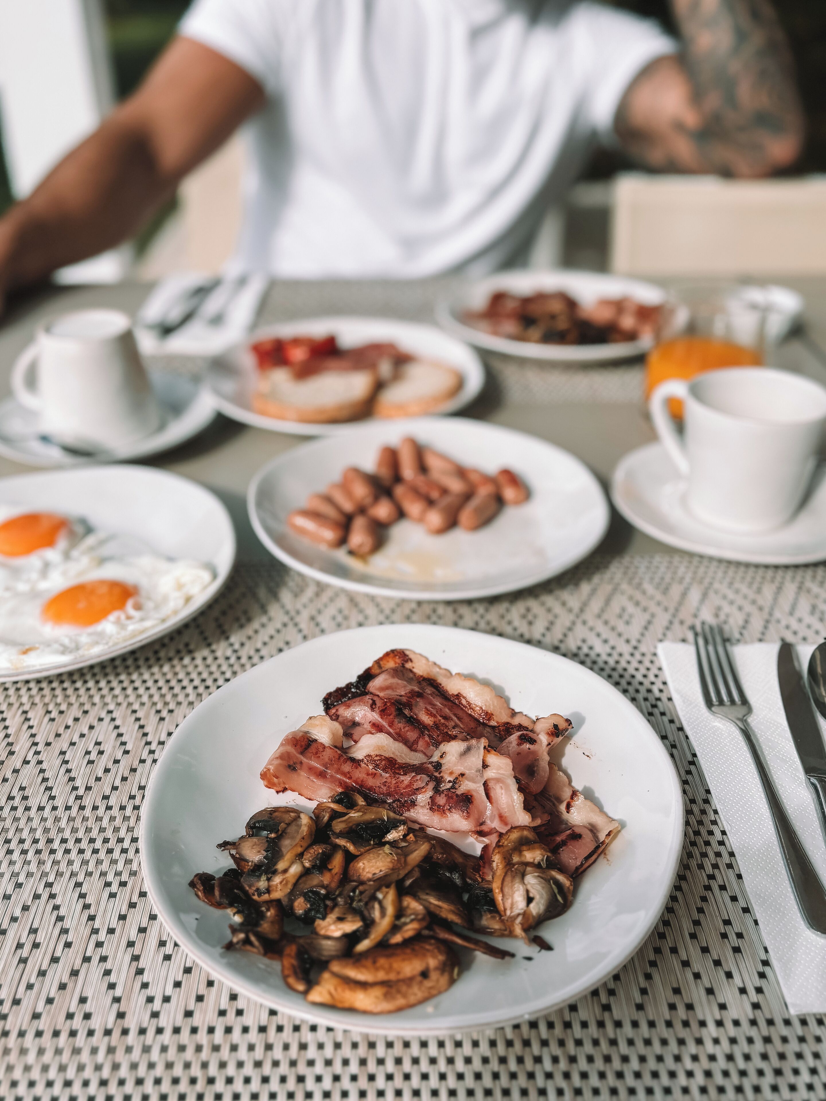 Une table de petit-déjeuner avec des assiettes remplies de nourriture, une tasse et des couverts.