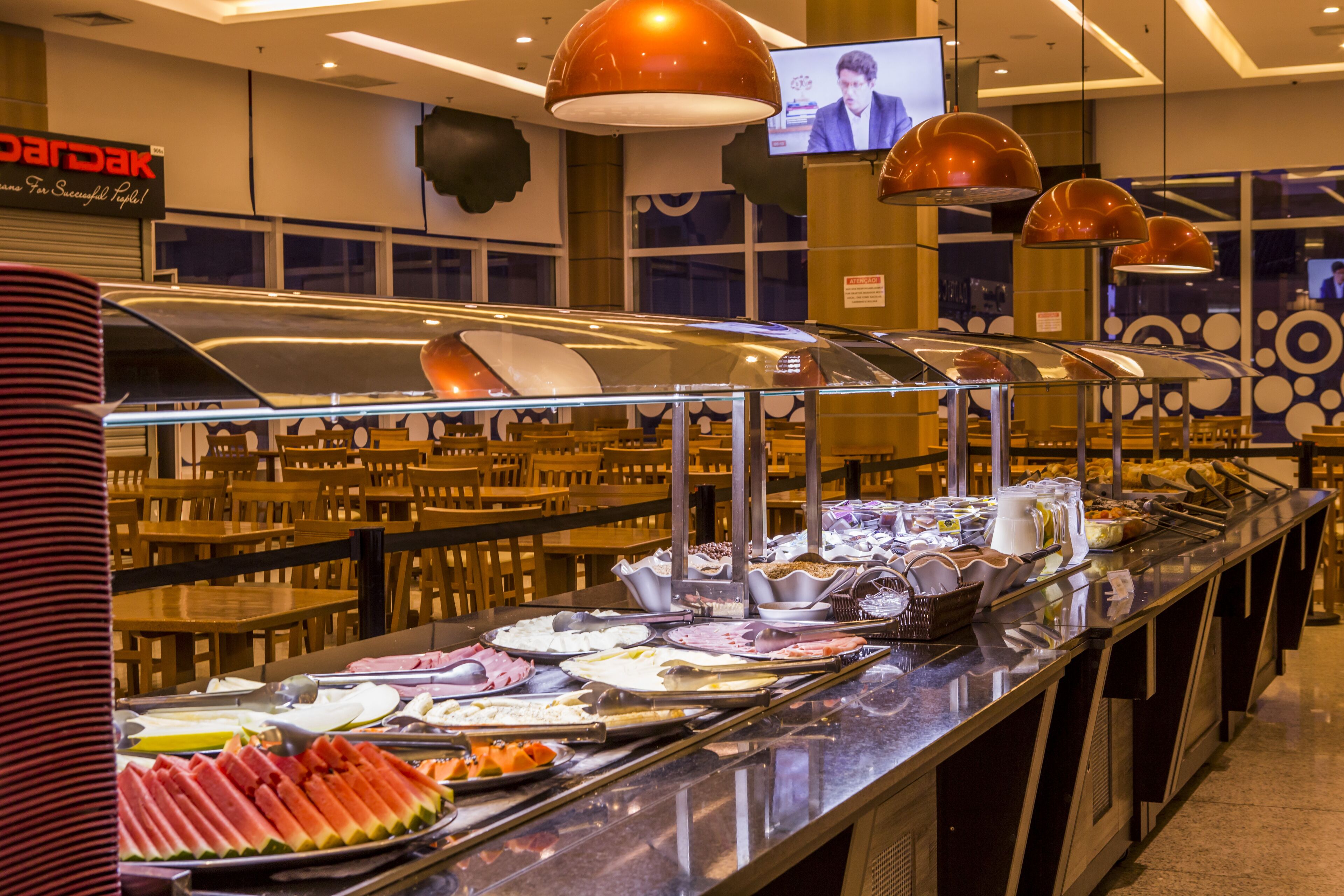 A buffet area with various food items and a television screen in the background.