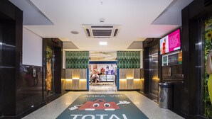 A hotel lobby with a reception desk, a digital screen, and a floor with a cartoon character and text. - Total Hotel (São Paulo)