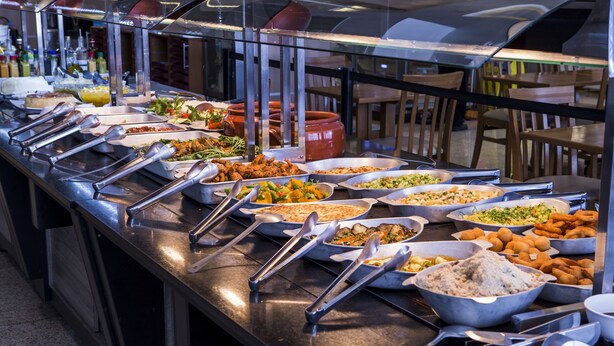A buffet with various dishes and utensils. - Total Hotel (São Paulo)