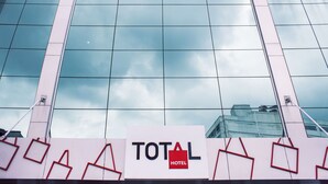 A hotel sign with the name "TOTAL HOTEL" against a modern building facade with reflective glass windows. - Total Hotel (São Paulo)