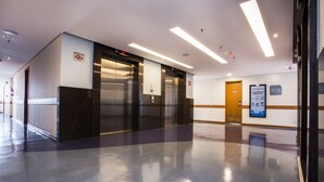 A modern elevator area with a polished floor, a digital display, and a fire safety sign. - Total Hotel (São Paulo)