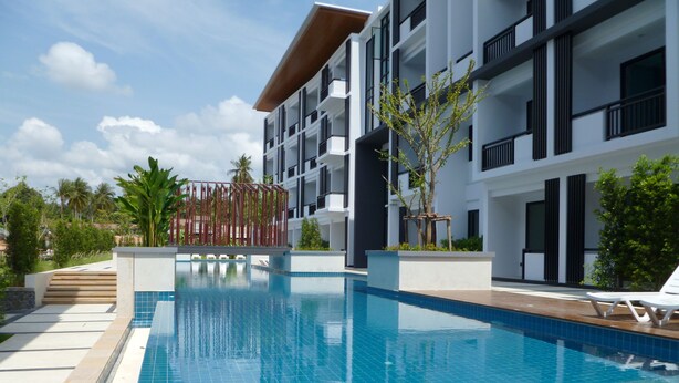 A modern hotel with a swimming pool, multiple balconies, and tropical landscaping. - V.O.P. Suite (Koh Samui)
