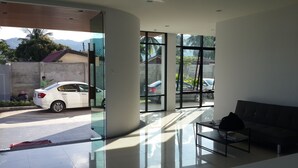 A modern hotel lobby with large windows, a reception desk, and a seating area. - V.O.P. Suite (Koh Samui)