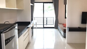 A modern kitchen with a built-in stove, a dining area with a table and chairs, and a balcony with a view. - V.O.P. Suite (Koh Samui)
