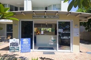 A reception and tour office with a sign for bike hire and a sign indicating late arrivals.