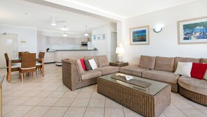 Un salon moderne avec un ensemble de canapés, une table à manger avec des chaises et une cuisine en arrière-plan.
