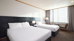 Une chambre d’hôtel avec deux lits, un bureau, une chaise et une grande fenêtre avec des rideaux.