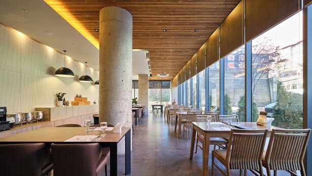 Un restaurant moderne avec un plafond en bois, de grandes fenêtres et une vaste salle à manger.