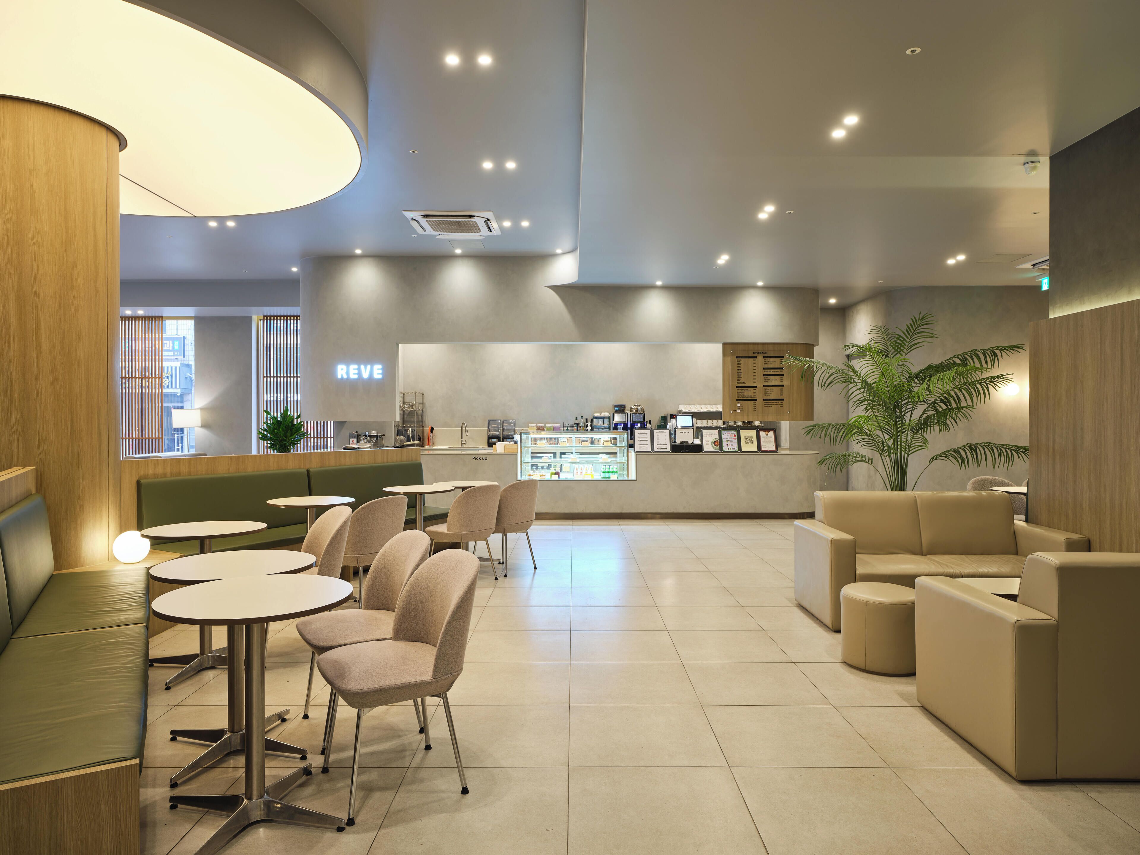 A modern cafe with seating areas, a counter, and a menu board.