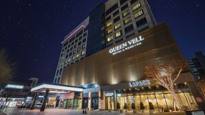 Un hôtel avec une enseigne bien visible indiquant « Queen Vell Hotel & Wedding » et « Lapace ».