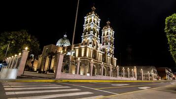 A historic church with two bell towers and a dome, featuring intricate architectural details and illuminated at night.