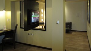 A hotel room with a flat-screen TV mounted on the wall, a desk with a chair, and a wooden floor. - Hotel Colonial (Teziutlan)