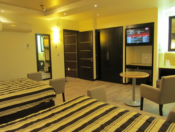 Habitación de hotel con cama, dos sillas, una mesita redonda, televisor y armario.