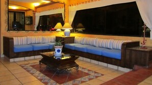 A living room with a sofa, a coffee table, and a large window with curtains. - Hotel Colonial (Teziutlan)
